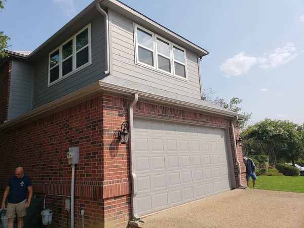 Seamless gutter installation on a two-story brick home in Joshua, TX (March 2026)